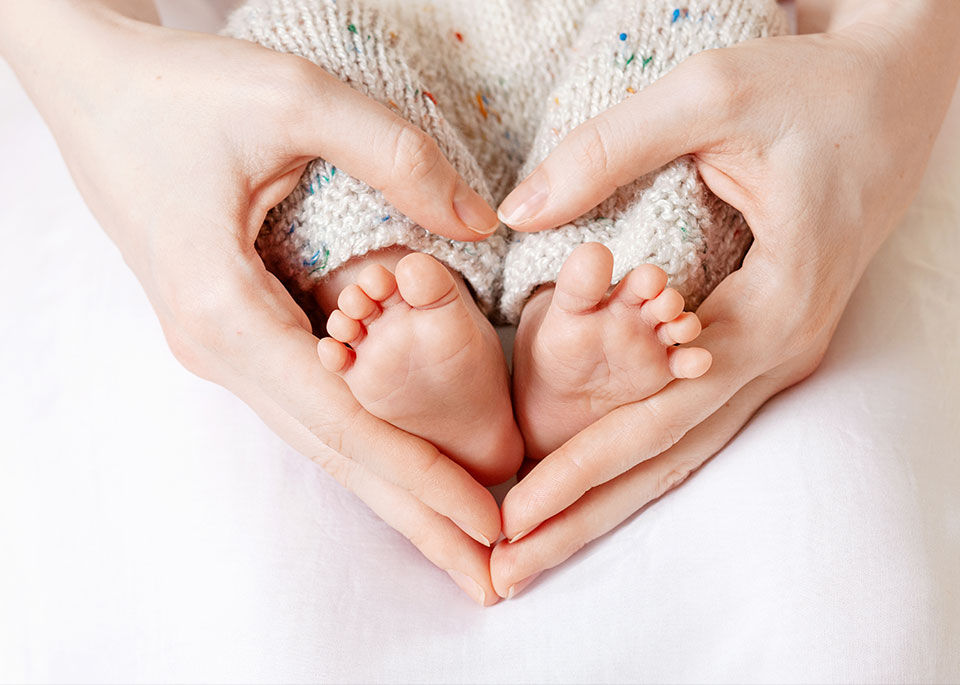 Baby Füße in den Händen der Mutter - Hände ergeben ein Herz